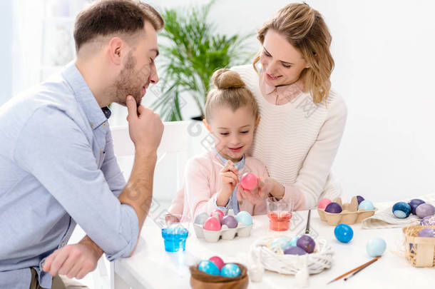 父母和女儿用不同的颜色画复活节彩蛋