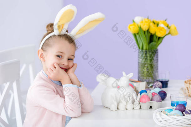 孩子在兔子耳朵由桌与复活节蛋