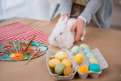 妇女与白色兔子在桌上与五颜六色的复活节彩蛋