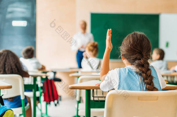<strong>学生</strong>在课后举手回答教师问题的后视图