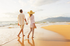 成熟夫妻在日落时分在沙滩上散步