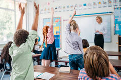 一群孩子在课堂上举手回答老师的问题