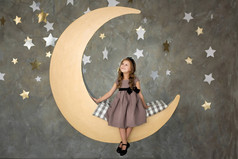 小女孩坐在大月亮上。小女孩的梦想