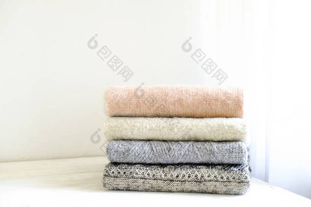 一束针织的保暖粉彩彩色毛衣, 用不同的针织图案折叠在白色木桌上, <strong>质感</strong>的墙壁背景。秋季冬季针织品。关闭, 复制文本空间