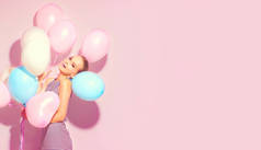 愉快的少女与五颜六色的空气气球有乐趣在粉红色背景