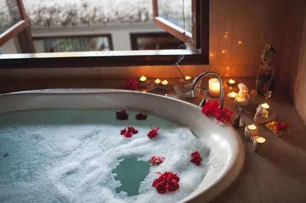 充满泡沫和花朵的大填充浴缸。浪漫的气氛, 卜