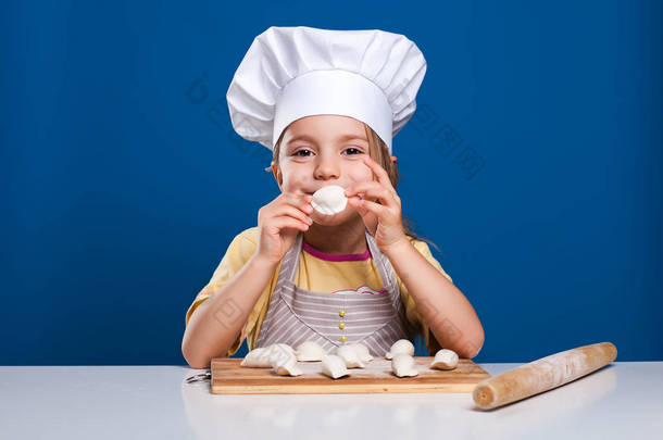 这个小女孩是烹调和准备食物在蓝色背景