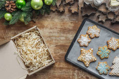 平躺在烤盘上的圣诞饼干, 圣诞花圈, 纸板箱和木制表面的饼干切割机