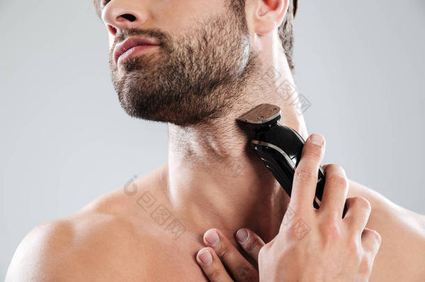裁剪图像的一个大胡子的男人，使用<strong>电动</strong>剃须刀