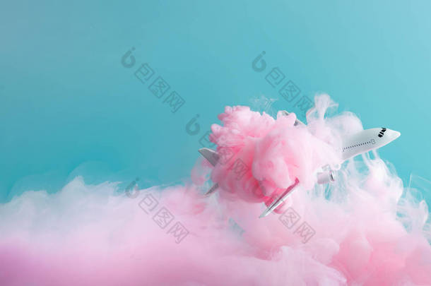 客机<strong>飞机</strong>玩具在柔和的粉红色云中飞行。旅游理念.
