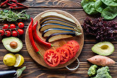 平躺与切开茄子、蕃茄和辣椒在切开板用新鲜的蔬菜在木表面附近