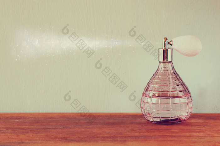 老式古董香水瓶与影响香水喷雾器木制的桌子