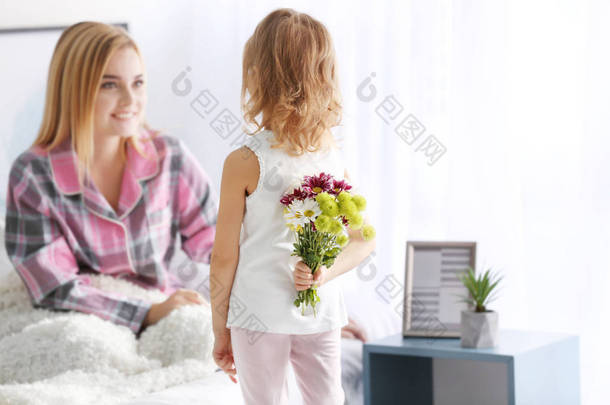 小女孩为她母亲背后隐藏的花束。母亲节的概念