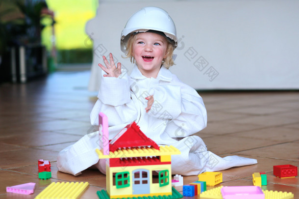 Toddler girl wearing safety helmet playing with building blocks