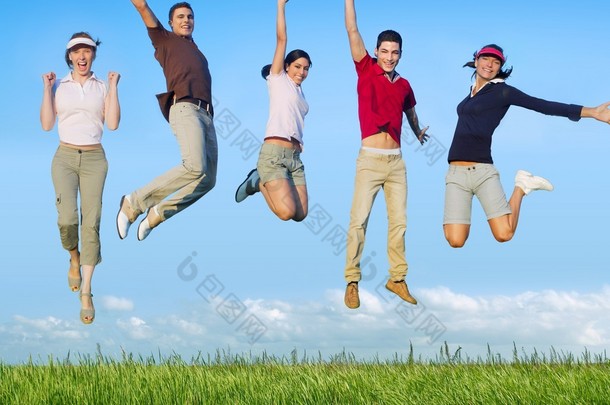 跳跃的年轻快乐集团在草地上