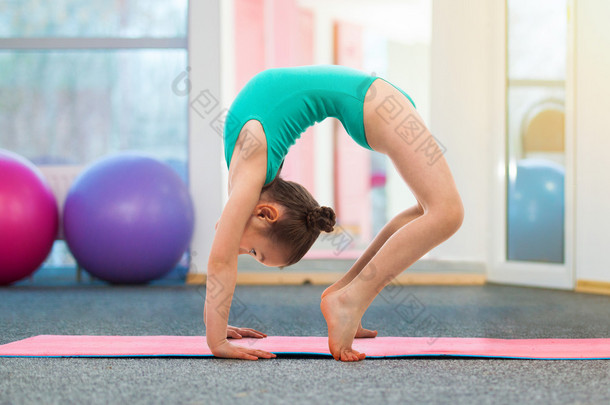 灵活小女孩体操运动员做在健身房的桥梁