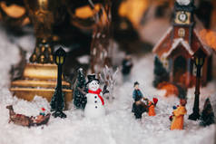 神奇的小圣诞城的缩影与雪, 雪人, 灯光, 人和儿童玩具, 树木和旧建筑。时尚的圣诞装饰在窗口。节日装饰, 冬季假期