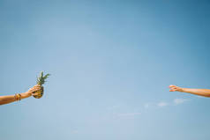 女人给另一个女人一个蓝色的天空菠萝水果 