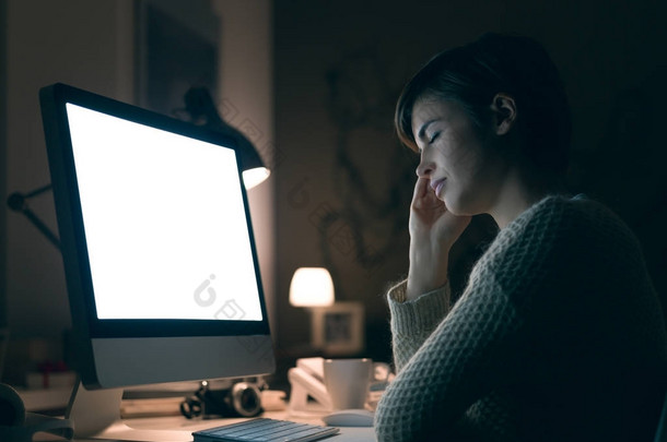 疲倦的年轻妇女在她的计算机工作在深夜, 她靠在她的手和闭眼睡觉