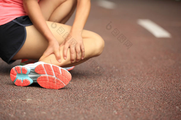 女跑步运动员举行她扭到脚踝受伤