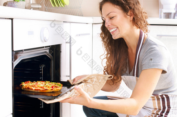 快乐的年轻女人在家做披萨