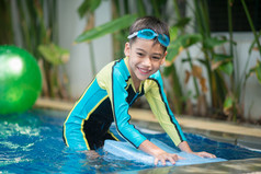 小混合亚洲阿拉伯男孩游泳在游泳池里酒店户外活动