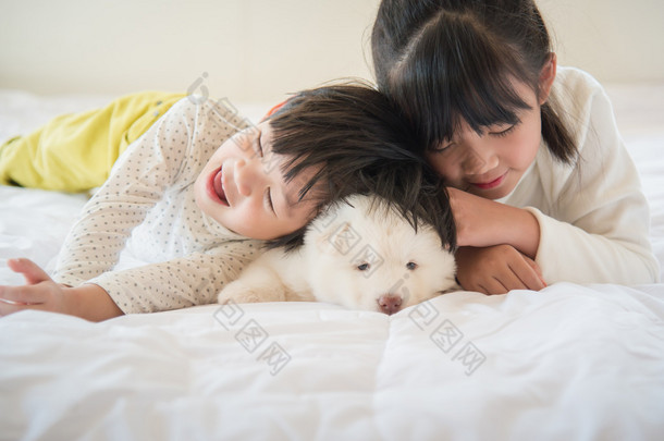 与亚洲儿童在白色的床上躺的西伯利亚哈士奇犬