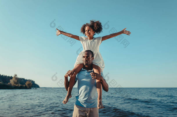 非洲裔美国父亲带着女儿在海滩上