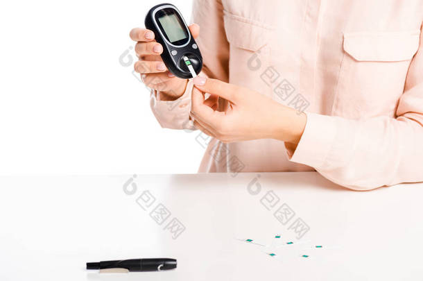 妇女把条带入血糖仪查出的白色, 糖尿病概念的裁剪图像