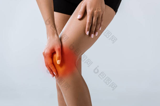 裁剪视图的女<strong>运动员</strong>与膝盖疼痛隔离在灰色