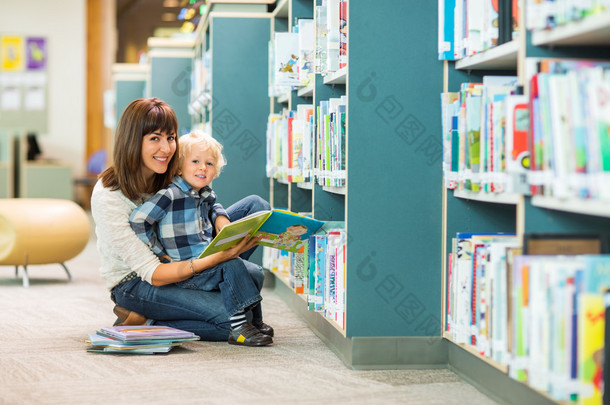 快乐的男孩和老师的阅读书在图书馆里