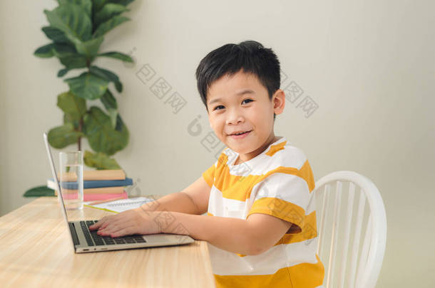 聪明英俊的亚洲十几岁前男孩在网上写作和使用电脑笔记本电脑学习课程.