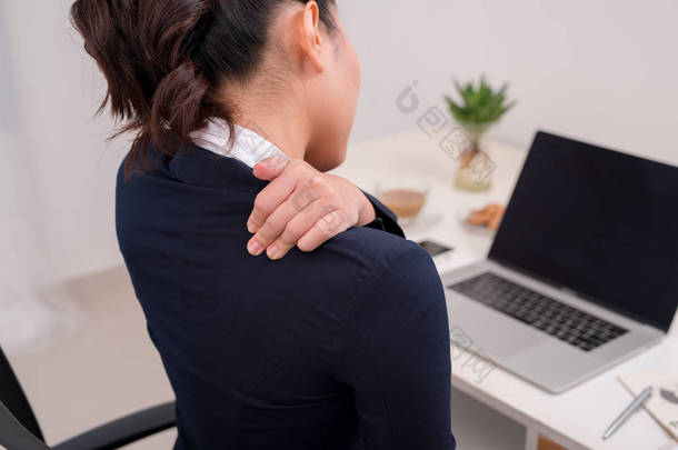 年轻的商业人颈部<strong>疼痛</strong>。将笔记本电脑放在桌面上以手放在颈部.