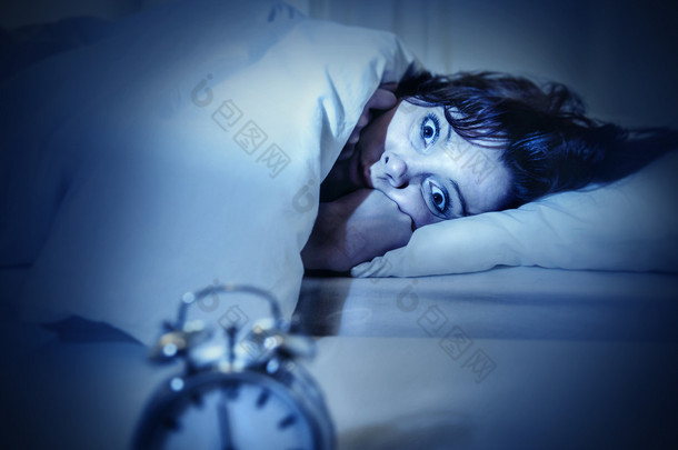 女人在床上用眼睛打开痛苦失眠和睡眠障碍 
