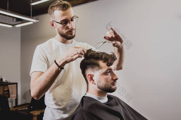在理发店理发的年轻人. 理发师负责理发和修剪<strong>胡子</strong>. 概念理发店.