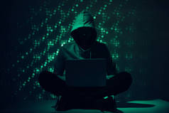 用膝上型电脑在帽衫中的黑客剪影的色调图片