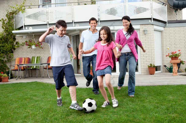 幸福的家庭，在他们的后院踢足球