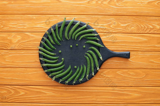 木桌顶圆板上的鲜绿色豌豆的顶部视图 