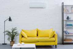 现代起居室内的黄色沙发和空调挂在白墙上