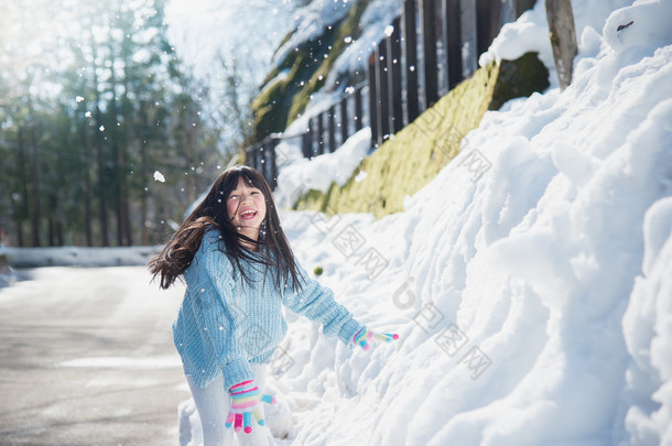 亚洲女孩在雪中户外微笑在寒冷的冬天里