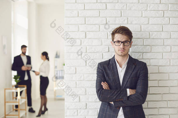 严肃的商人穿着休闲装站在白墙上的一间白色办公室里.