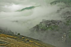 神秘的山丘和村庄在雾中。有薄雾的秋天风景与米梯田。中国, 阳朔, 龙胜