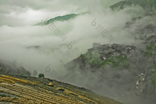 神秘的山丘和村庄在雾中。有薄雾的秋天风景与米梯田。中国, 阳朔, 龙胜