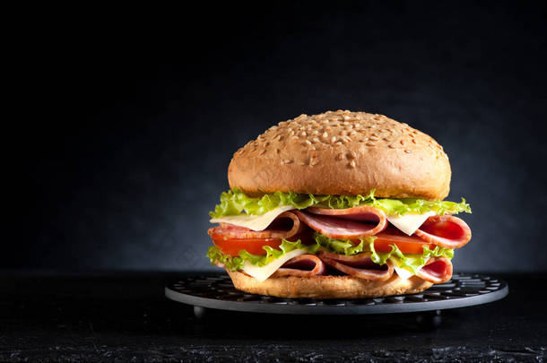 在黑色背景上的蔬菜和<strong>火腿</strong>奶酪三明治汉堡