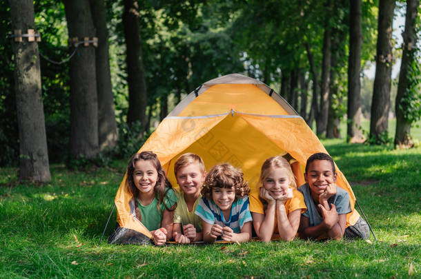 快乐的多元文化的孩子<strong>微笑</strong>，而躺在营地附近 