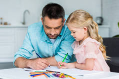 父亲和可爱的小女儿画与彩色铅笔一起在家里  