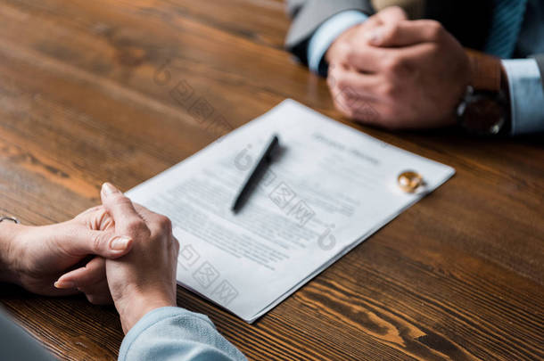 部分观点的律师和客户坐在桌子上与离婚令和结婚戒指 