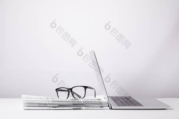 <strong>笔记本</strong>电脑和眼镜堆的报纸上, 白色