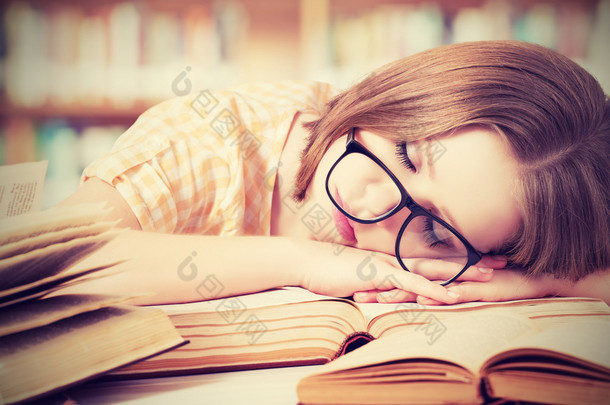 图书馆图书疲倦的学生女孩戴着眼镜睡觉