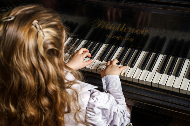 可爱的小女孩玩音乐学校的钢琴